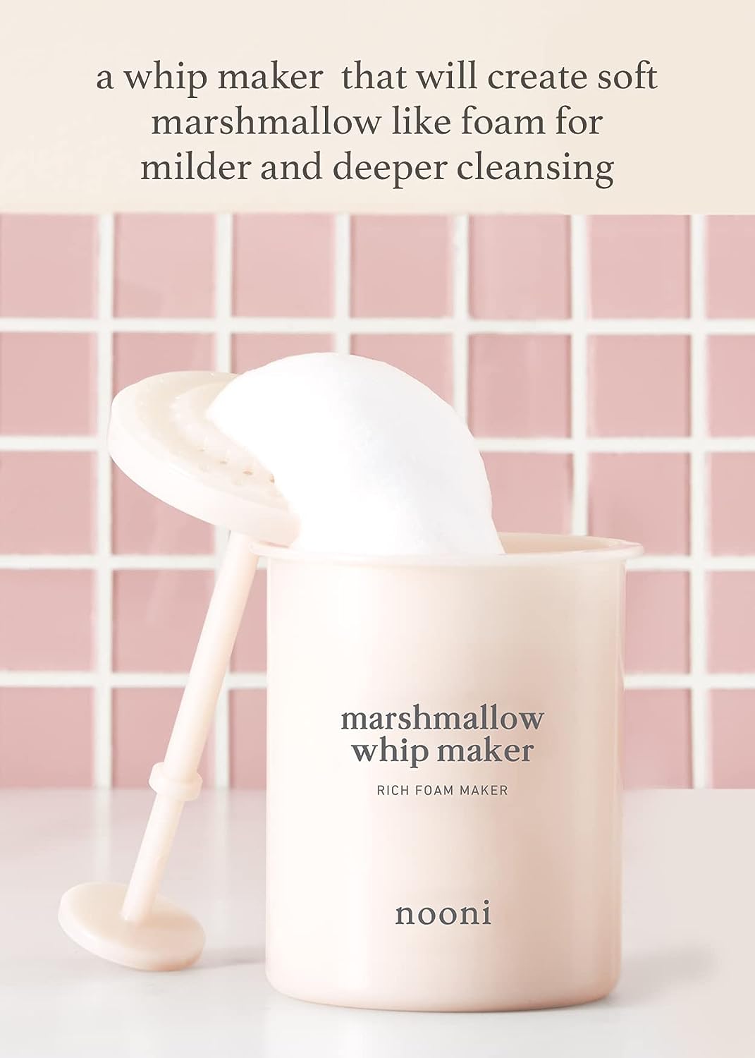 Nooni Marshmallow Whip Maker with foam against a pink tile bathroom background