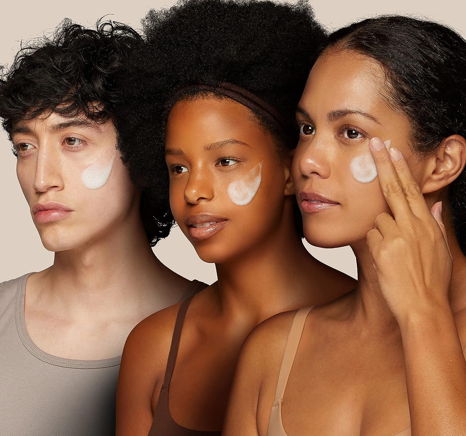 Three models with diverse skin tones applying Nooni cleanser foam to their faces