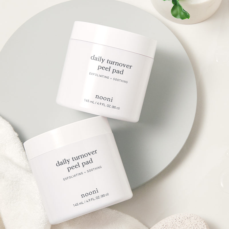 Two Nooni Daily Turnover Peel Pad products resting on a towel