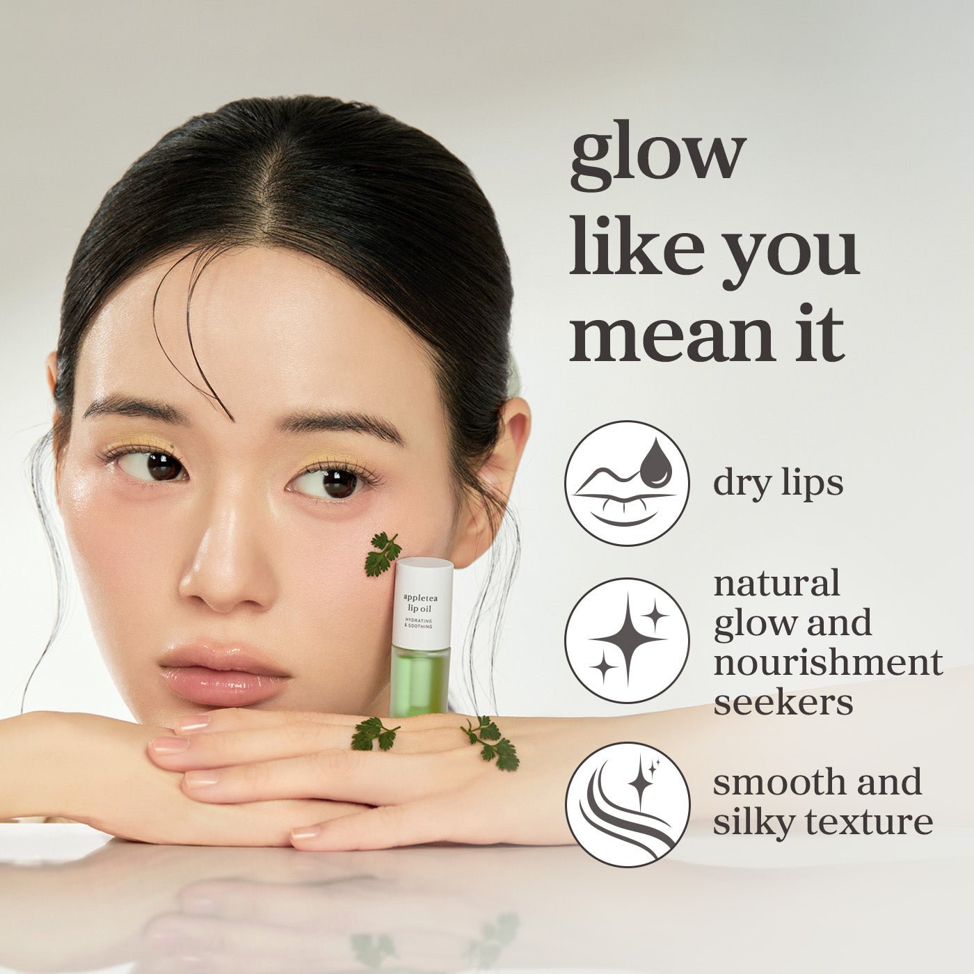 Model holding nooni appletea lip oil highlighting glossy lips, natural glow, and a smooth, silky finish.