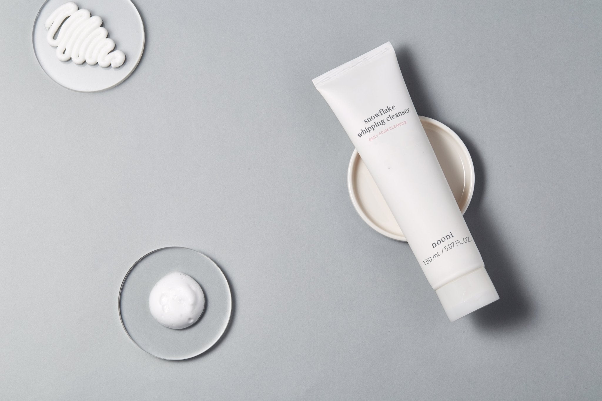 Snowflake whipping cleanser with soft foam swatches placed on plates highlighting airy texture and smooth consistency.