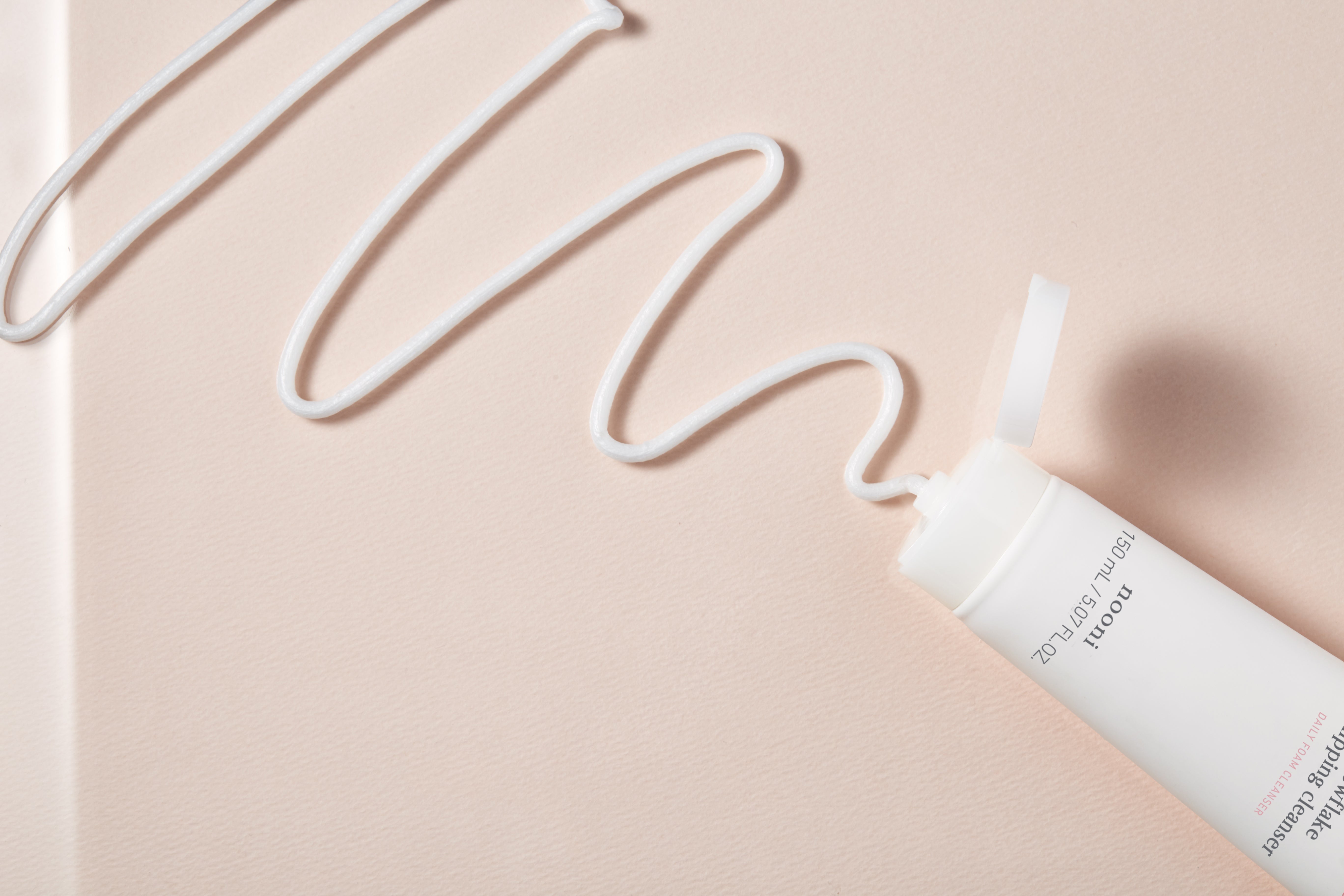 Squeezing the cream texture from a tube of Nooni Snowflake Whipping Cleanser