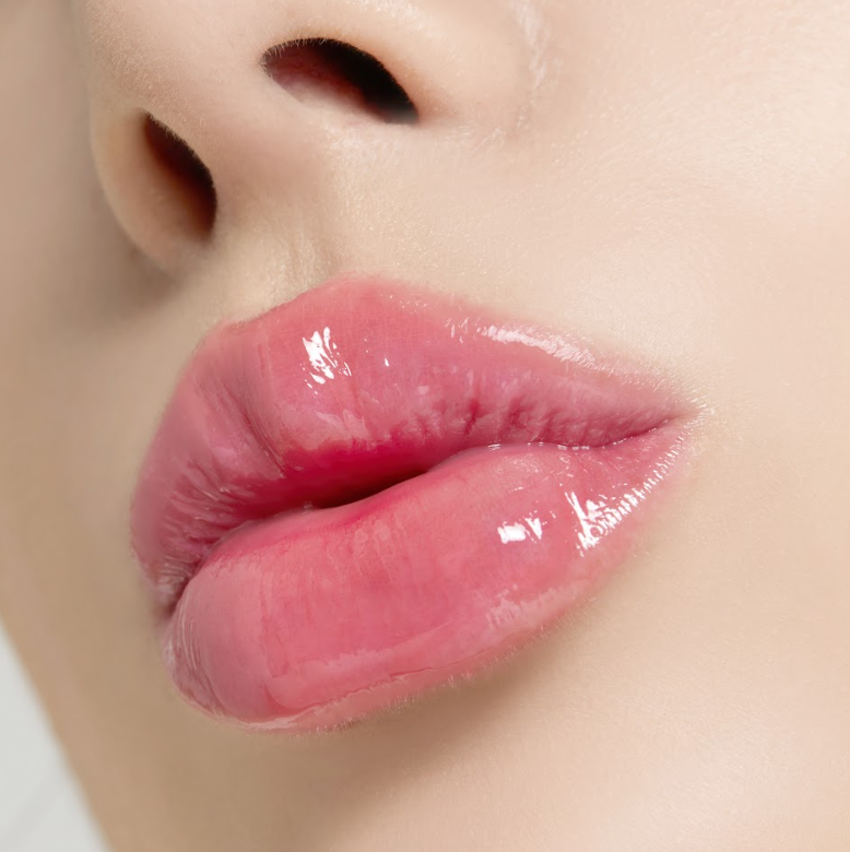 Close-up of moist, glossy, reddish-tinted lips after applying Nooni appleberry lip oil