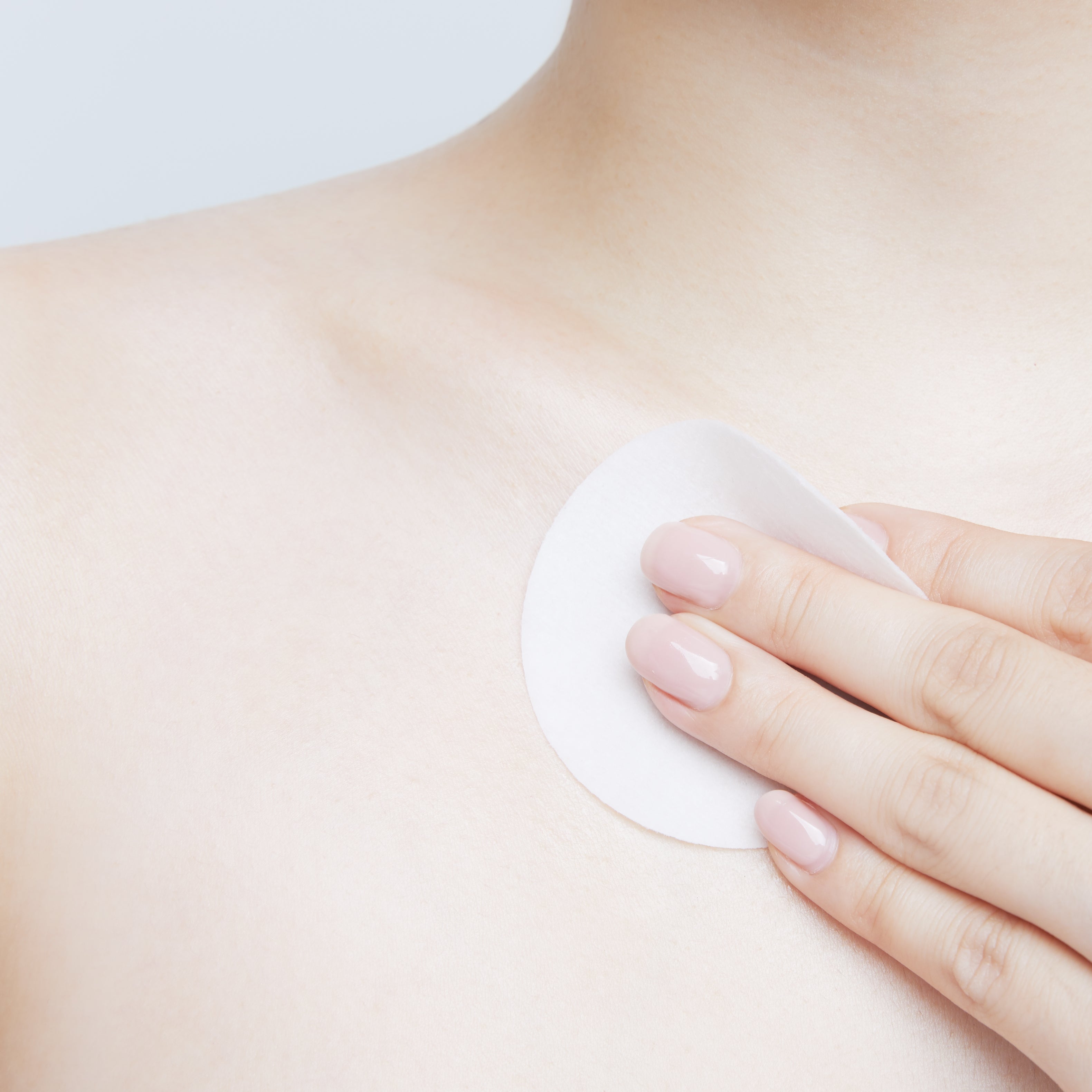 Using Nooni peel pad to exfoliate skin on the collarbone and shoulder area