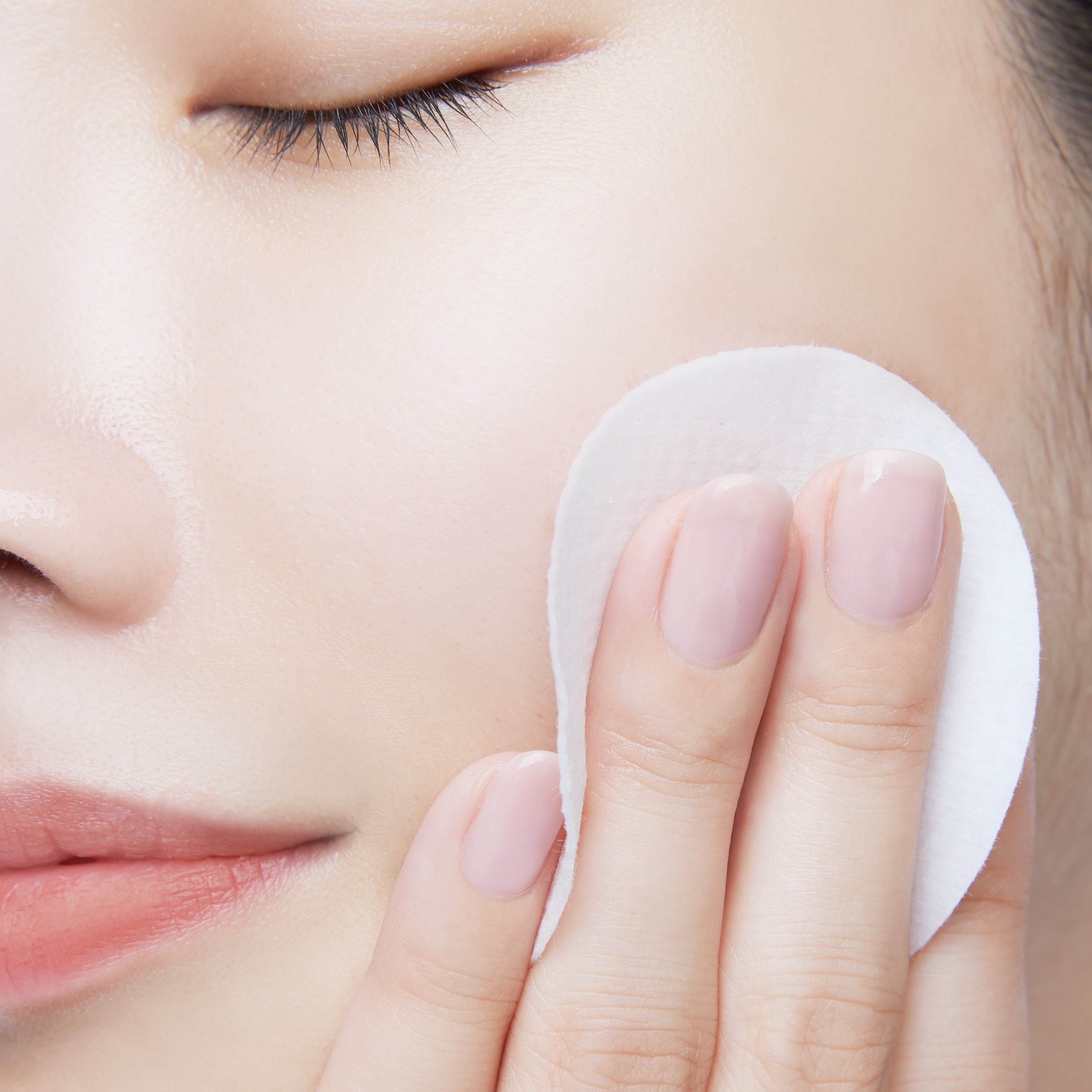 Close-up of gently wiping the cheek with a Nooni peel pad