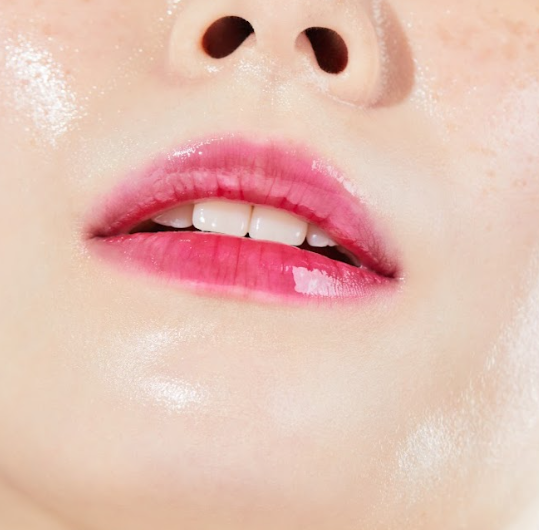 Close-up of moist, glossy, tinted lips after applying Nooni applewine lip oil