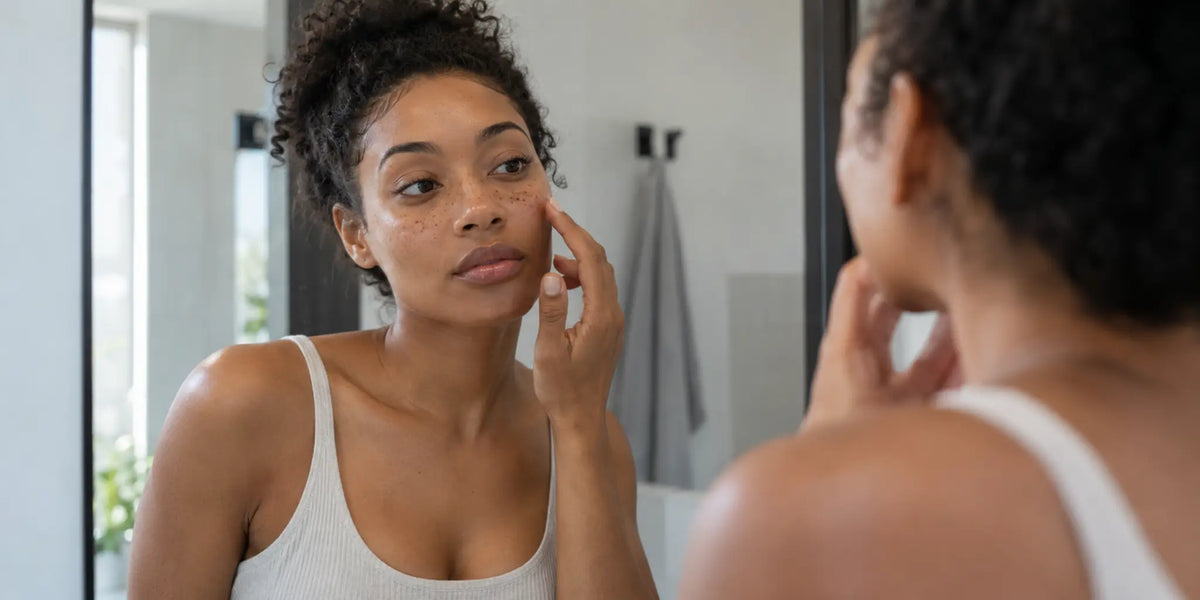 Woman checking subtle faux freckles in a bathroom mirror before cleansing