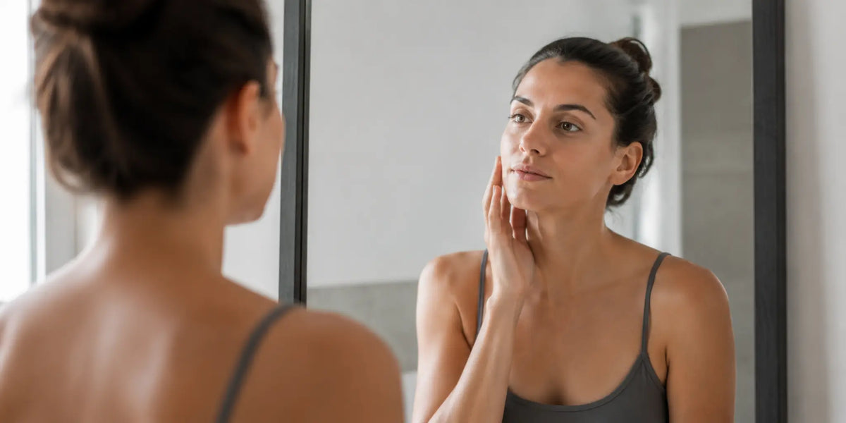 Woman checks her facial self-tan in a mirror before washing