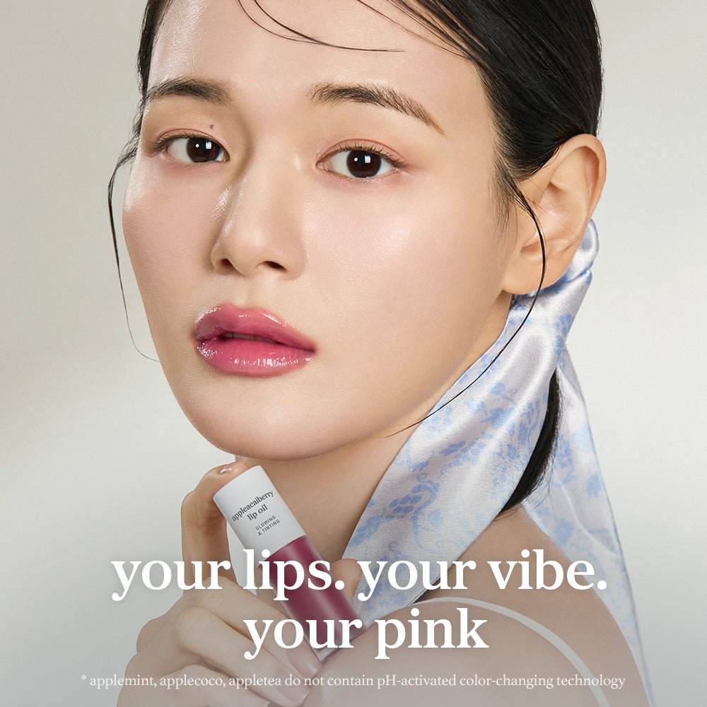 Model applying nooni appleacaiberry lip oil with glossy lips and lip applicator close up.