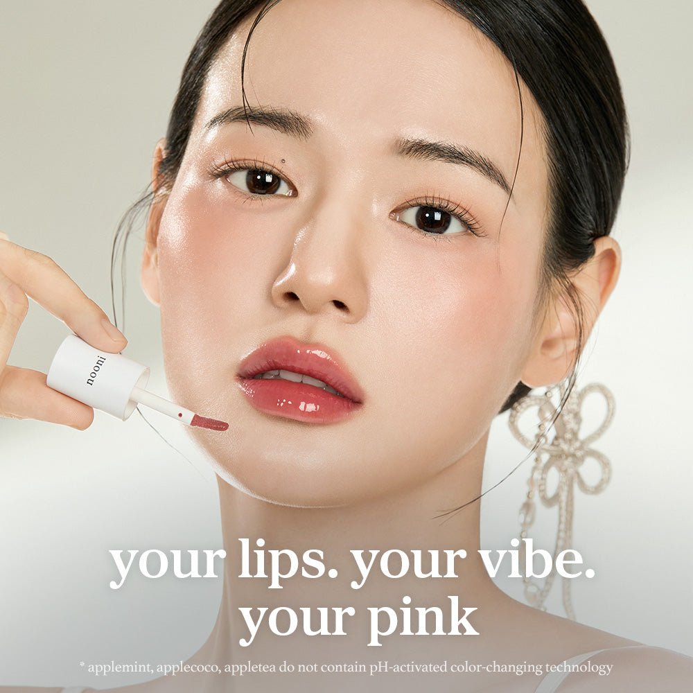 Model applying nooni applevanilla lip oil with glossy lips and lip applicator close up.